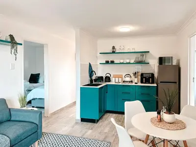 a kitchen with blue cabinets and a living room at Ebb & Flow in Hermanus