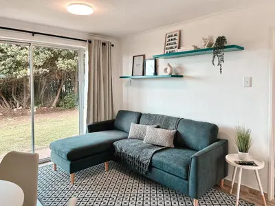 a living room with a blue couch and a window at Ebb & Flow in Hermanus