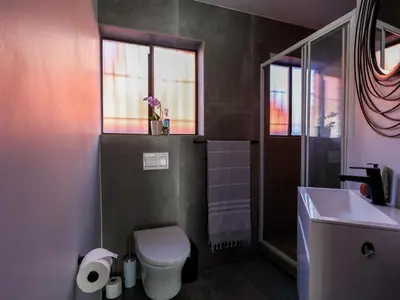 a bathroom with a toilet and a sink and a window at Imoyo Ocean Retreat in Hermanus
