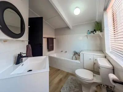 a bathroom with a toilet and a tub and a sink at Imoyo Ocean Retreat in Hermanus