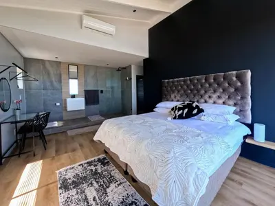 a bedroom with a large bed and a desk at Imoyo Ocean Retreat in Hermanus
