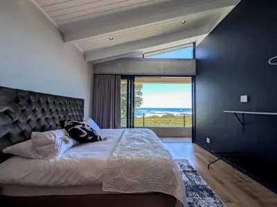 a bedroom with a large bed with a large window at Imoyo Ocean Retreat in Hermanus