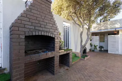 a brick fireplace in a yard next to a house at Serena Inn Room 8 in Cape Town
