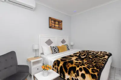 a bedroom with a leopard print bed and a chair at Serena Inn Room 8 in Cape Town