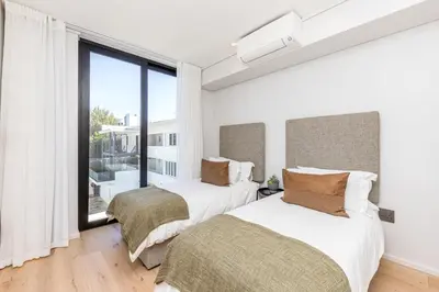 two beds in a bedroom with a large window at Aan de Meul Luxury Apartments in Stellenbosch
