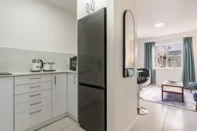 a kitchen with white cabinets and a black refrigerator at Manhattan Square 17 in Cape Town