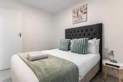 a bedroom with a large bed with a black headboard at Manhattan Square 17 in Cape Town