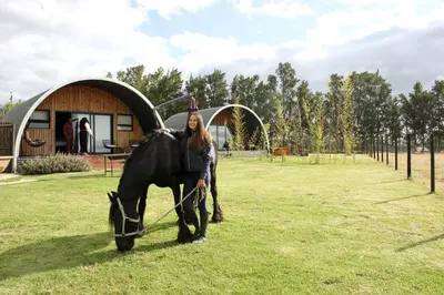 a woman standing next to a black horse in a field at La Vita Romantic Getaway Cabin in Wellington