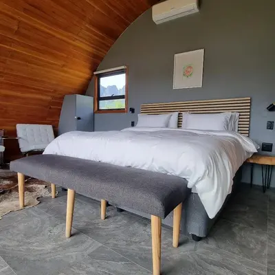 a bedroom with a large white bed with a bench at La Vita Romantic Getaway Cabin in Wellington