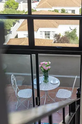 a table and chairs on a balcony with a vase of flowers at 2 Bedroom, Mountain View Penthouse, Century City in Cape Town