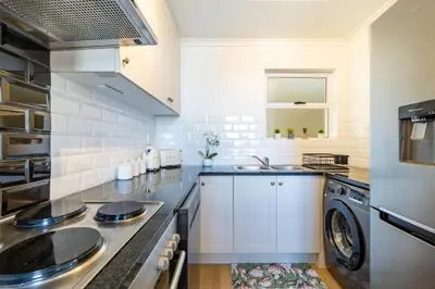 a kitchen with a sink and a washer and dryer at 2 Bedroom, Mountain View Penthouse, Century City in Cape Town