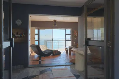 a living room with a chair and a view of the ocean at Gordons Bay Villa with Pool in Gordonʼs Bay