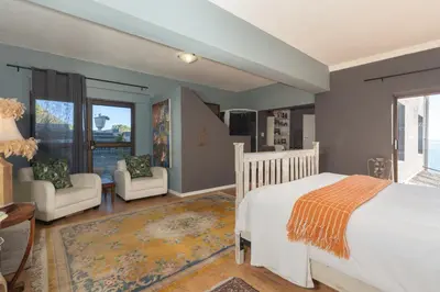 a bedroom with a white bed and two chairs at Gordons Bay Villa with Pool in Gordonʼs Bay
