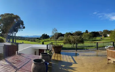 a patio with a view of a golf course at The Welgemoed Guest House in Bellville