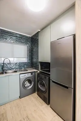 a kitchen with a refrigerator and a washer and dryer at The Lagoon Beachfront Apartment in Cape Town