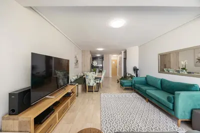 a living room with a green couch and a television at The Lagoon Beachfront Apartment in Cape Town