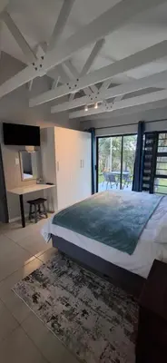 a bedroom with a bed and a table and a desk at Kiewiets Nest in Victory Hill