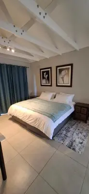 a bedroom with a large bed with two pictures on the wall at Kiewiets Nest in Victory Hill