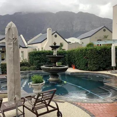 a fountain in the middle of a courtyard with a chair at Apartment Franschhoek 121 Lermitage in Franschhoek