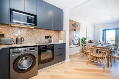 a kitchen with a washing machine and a dining room at Paarl 225 - Lux Modern 2 Bedroom Apartment with Parking in Paarl