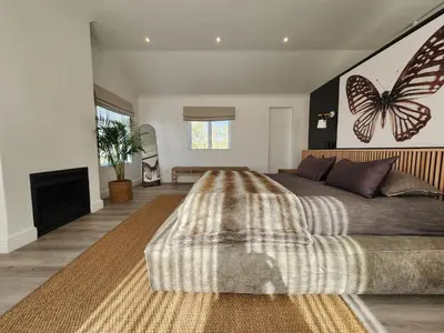 a bedroom with a large bed with a butterfly on the wall at Luxury Flamingo Villa at beach with Pool and Solar Back Up in Cape Town
