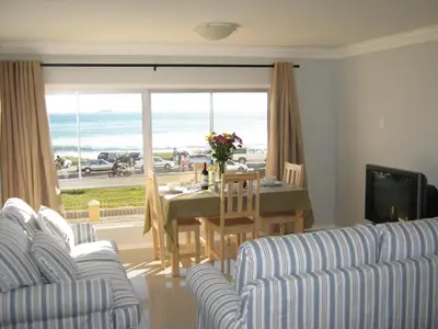 a living room with a table with a view of the ocean at Aandvari Zeezicht in Cape Town