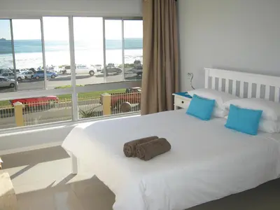 a bedroom with a bed with a view of the beach at Aandvari Zeezicht in Cape Town