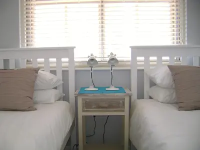 a bedroom with two beds and a table with two lamps at Aandvari Zeezicht in Cape Town