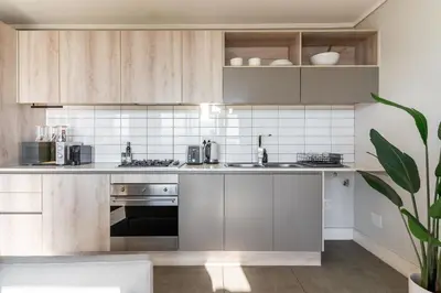 a kitchen with stainless steel appliances and wooden cabinets at Waters Edge Apartments by Propr in Cape Town