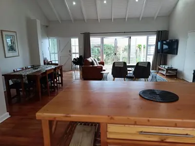 a living room with a large wooden table and chairs at Rockwest 1 Cosy summer holiday house Hermanus in Hermanus