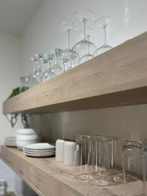 a wooden shelf with wine glasses and plates on it at Inside Out Bliss in Paarl