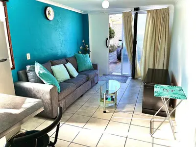 a living room with a couch and a blue wall at Cosy Flatlet in Chrismar in Stikland