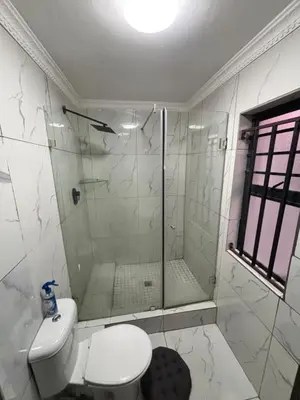 a white bathroom with a shower and a toilet at Browns villa and construction pty ltd in Cape Town