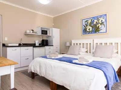 a bedroom with a large bed and a kitchen at Mountain Rest Hermanus in Hermanus