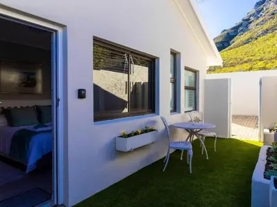 a bedroom with a bed and a table and a window at Mountain Rest Hermanus in Hermanus