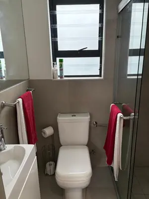 a bathroom with a toilet and a sink and a window at Studio Apartment in Cape Town in Cape Town