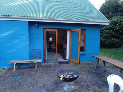 a blue house with a grill and a table and bench at Yellowwood Place in Bettyʼs Bay