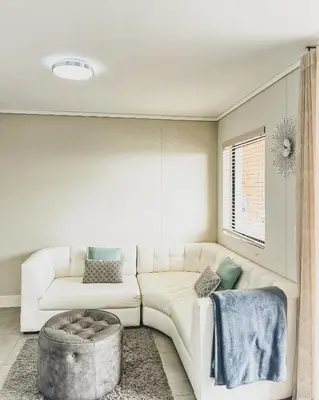 a living room with a white couch and a ottoman at Modern One Bedroom Apartment Next to Canal Walk Mall in Cape Town