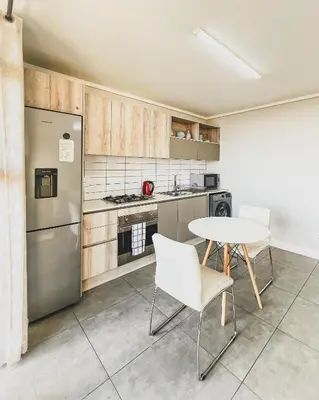 a kitchen with a table and a refrigerator at Modern One Bedroom Apartment Next to Canal Walk Mall in Cape Town
