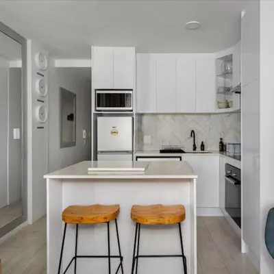 a kitchen with white cabinets and wooden stools at JC Mountain View in Cape Town