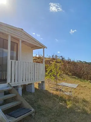 a house with a porch and a bench next to it at Cabin on Spinlea Farm Campsite in Caledon