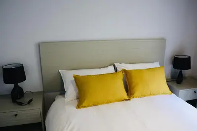 a bedroom with a white bed with yellow pillows at 21b on SANDOWN in Cape Town