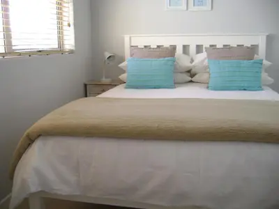 a bedroom with a large bed with blue pillows at Aandvari Sunset Court in Cape Town