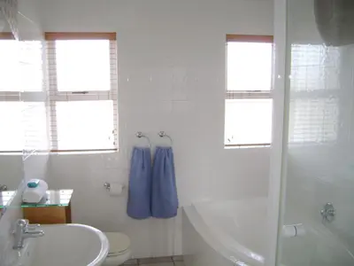 a white bathroom with a tub and a sink at Aandvari Sunset Court in Cape Town