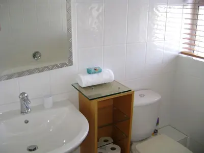 a white bathroom with a sink and a toilet at Aandvari Sunset Court in Cape Town