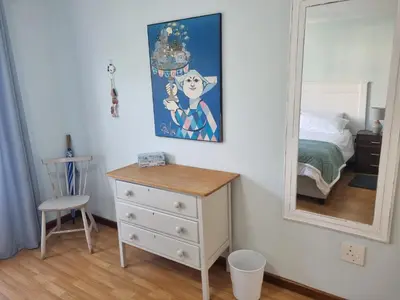 a bedroom with a dresser and a mirror at Sea Urchin in Gordonʼs Bay