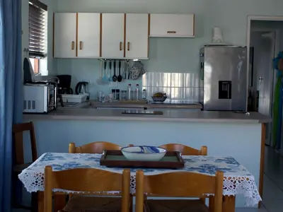 a kitchen with a table and chairs and a refrigerator at Sea Urchin in Gordonʼs Bay