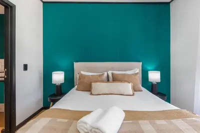 a bedroom with a large bed with a green wall at Nine Palms - Century City Luxury Apartment in Cape Town