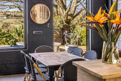 a table with chairs and a vase of flowers on a patio at My Venue at Avemore in Onder-Papegaaiberg