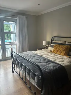 a bedroom with a bed and a large window at Pool & Garden Winelands Retreat in Stellenbosch